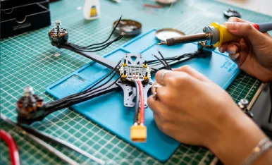 Man using a soldering iron to repair a drone.