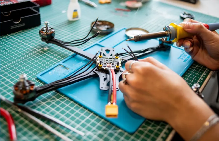 Man using a soldering iron to repair a drone.